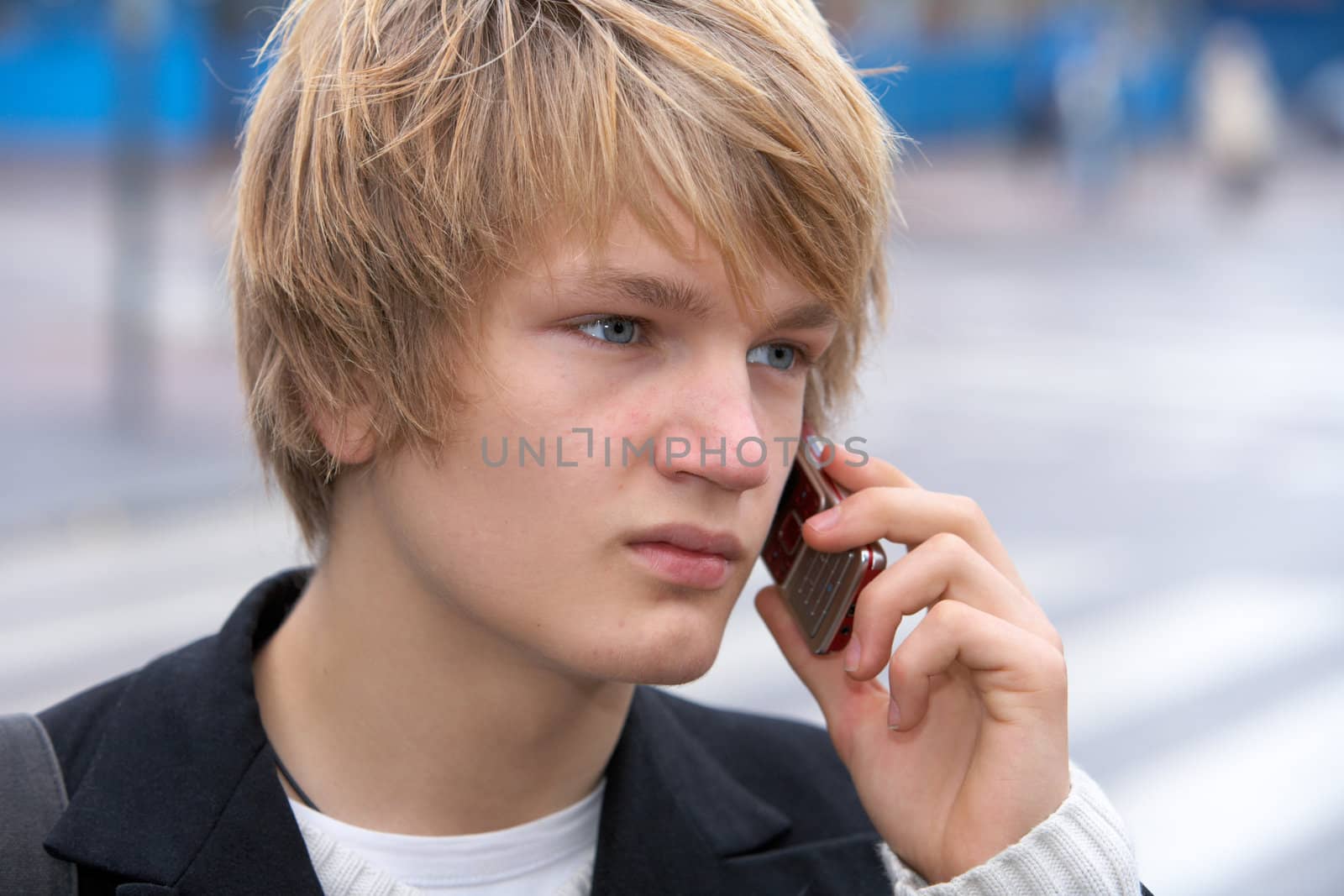 Teenage boy using mobile phone in street, close-up