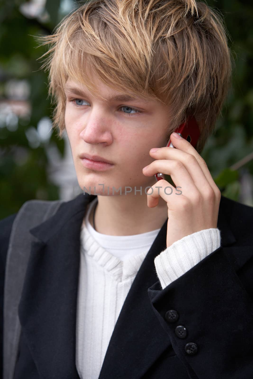 Teenage boy using mobile phone in city park, close-up