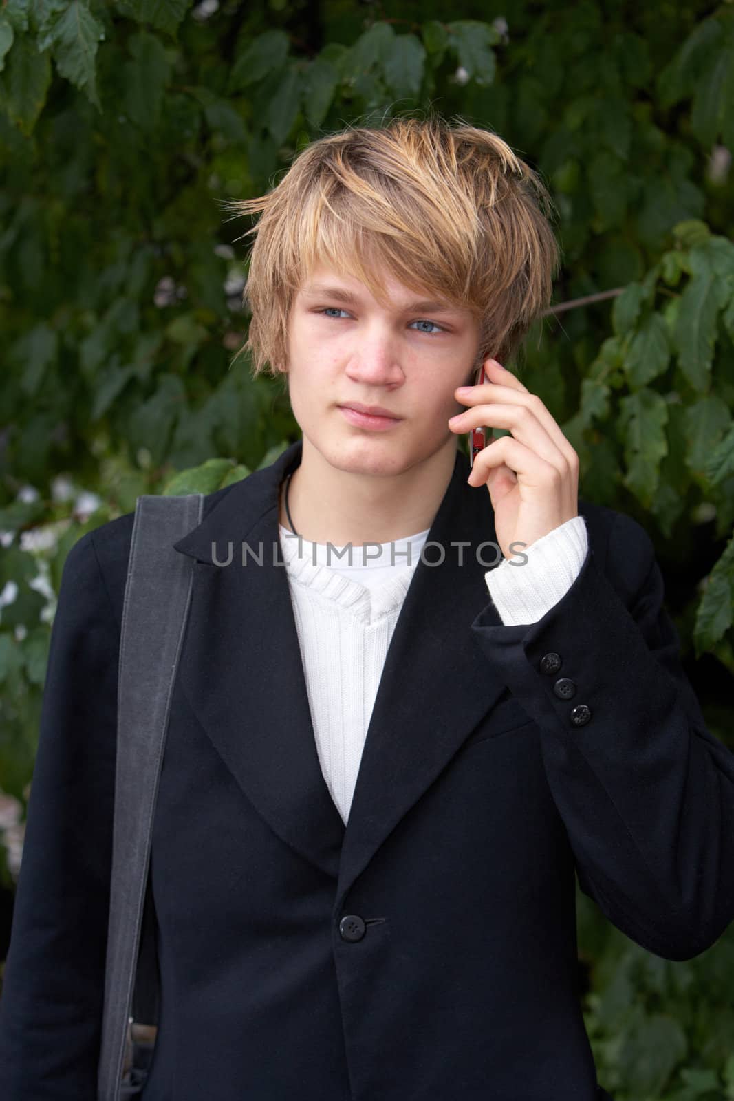 Teenage boy using mobile phone in city park, frontal view