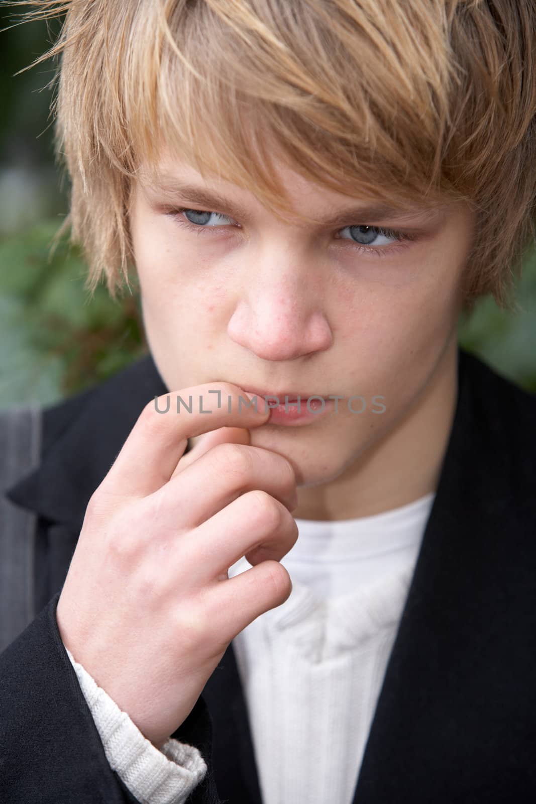Teenage boy contemplating in city park, frontal close-up