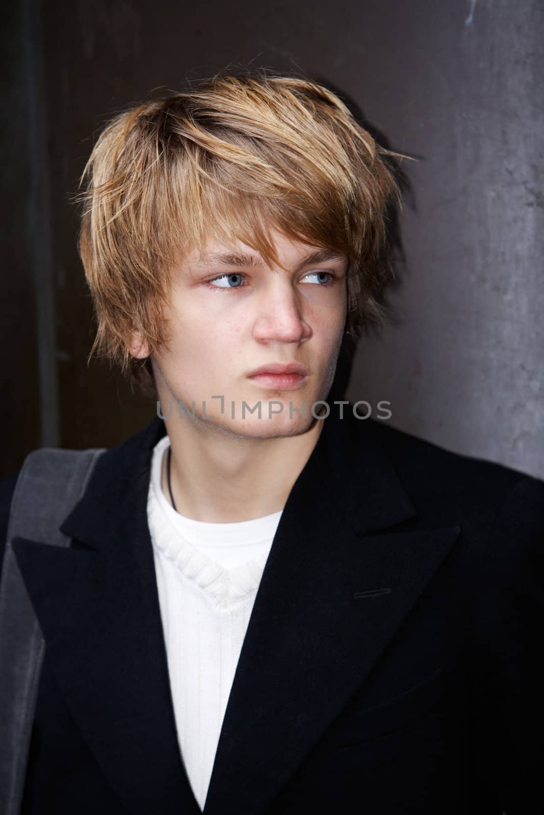 Portrait of teenage boy standing by wall, exterior