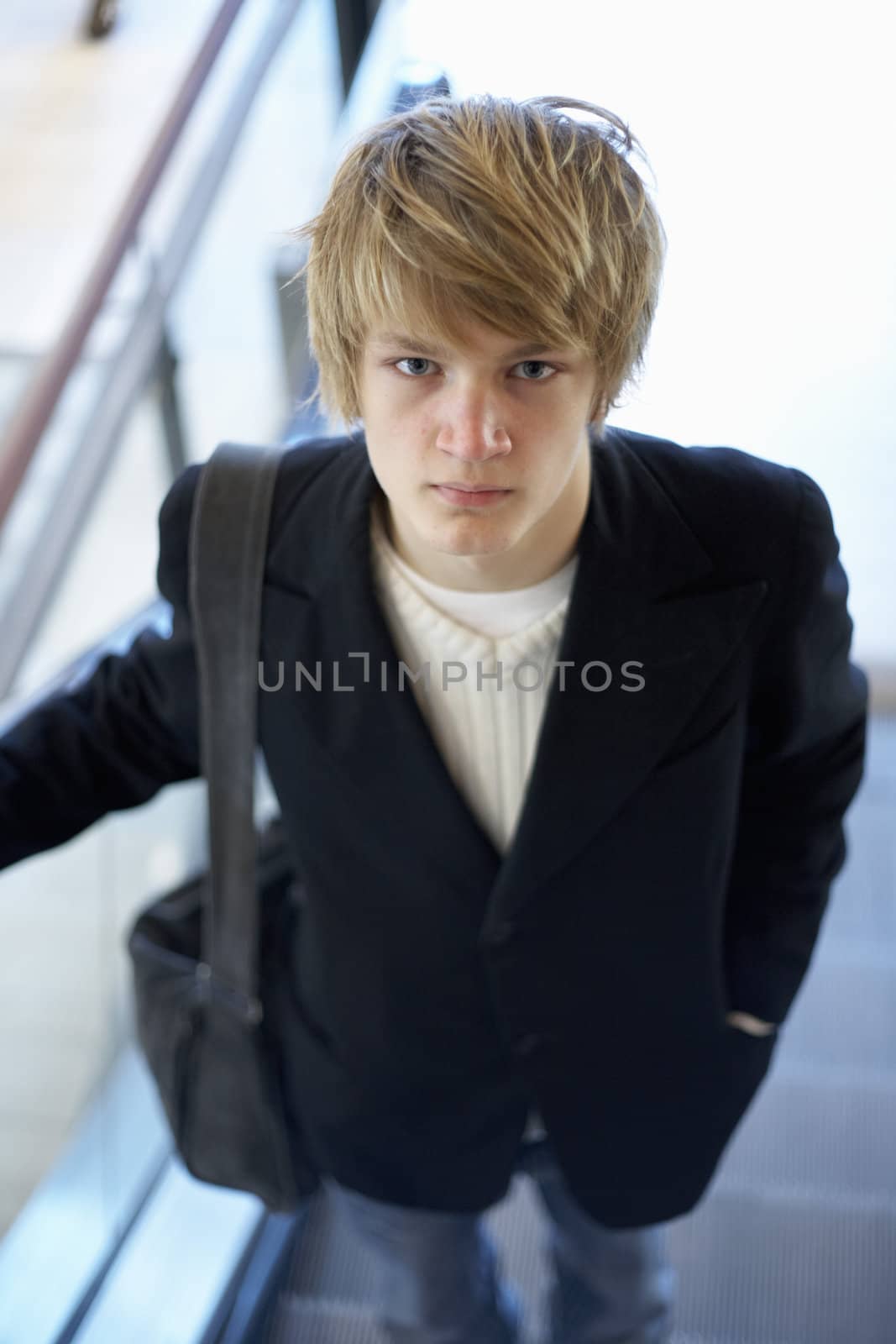 Interior shot of teenage boy standing in escalator