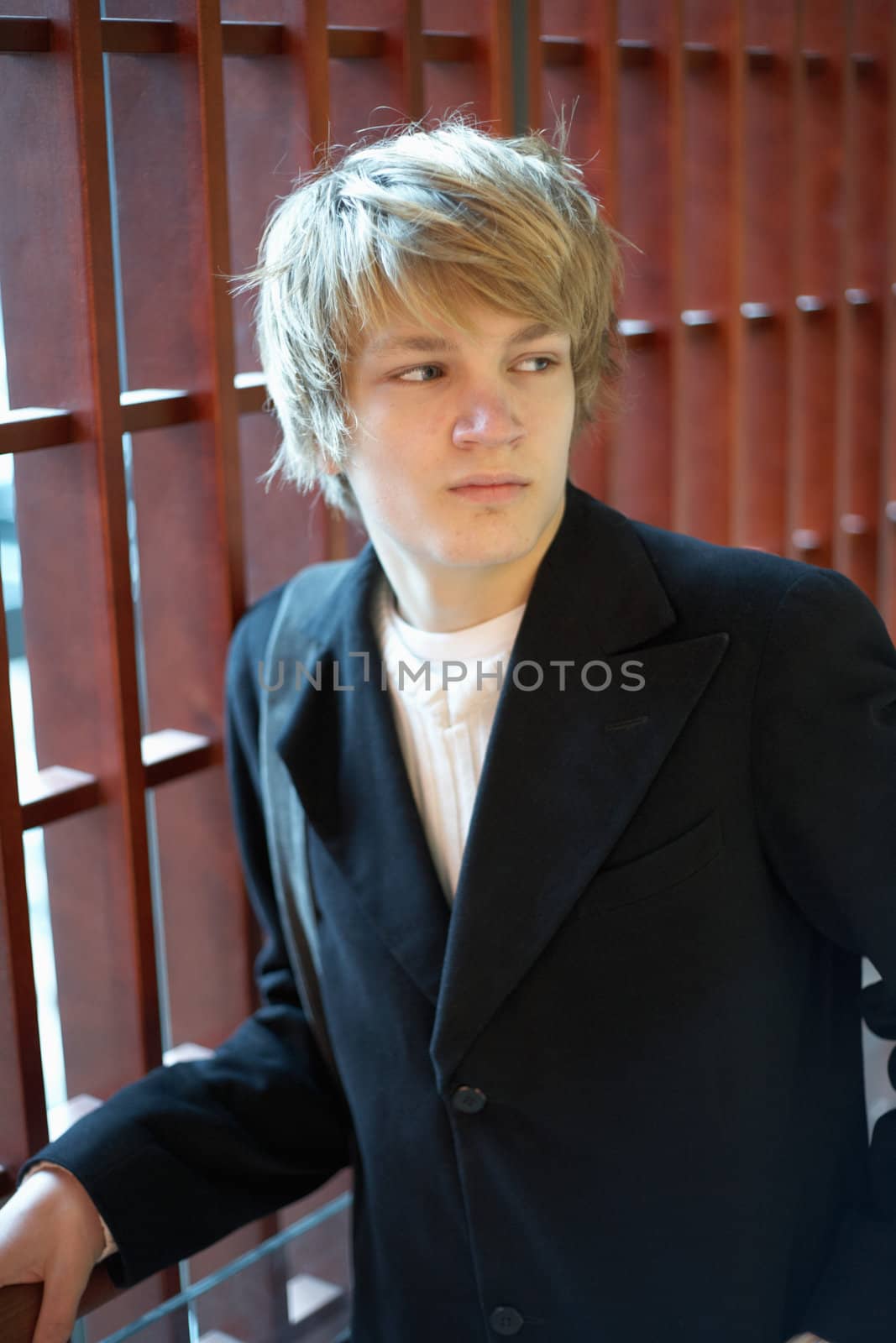 Interior shot of teenage boy leaning to wooden panel window