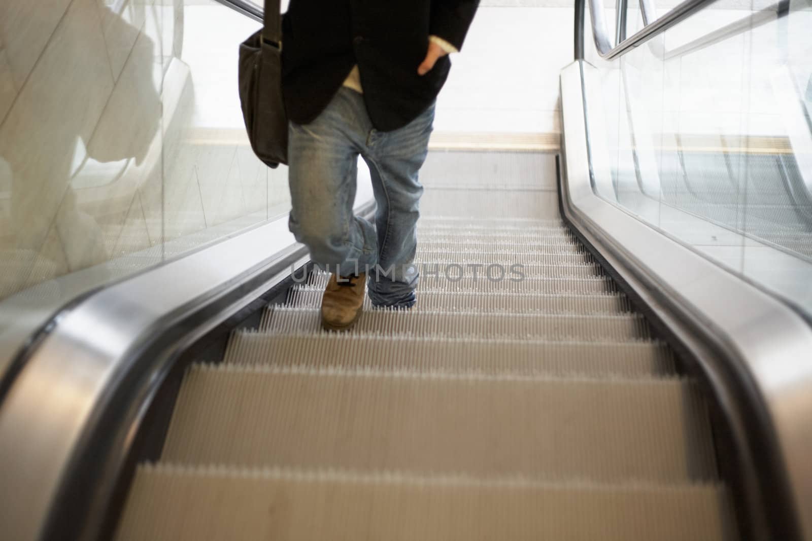 Teenager walking up in escalator, low section