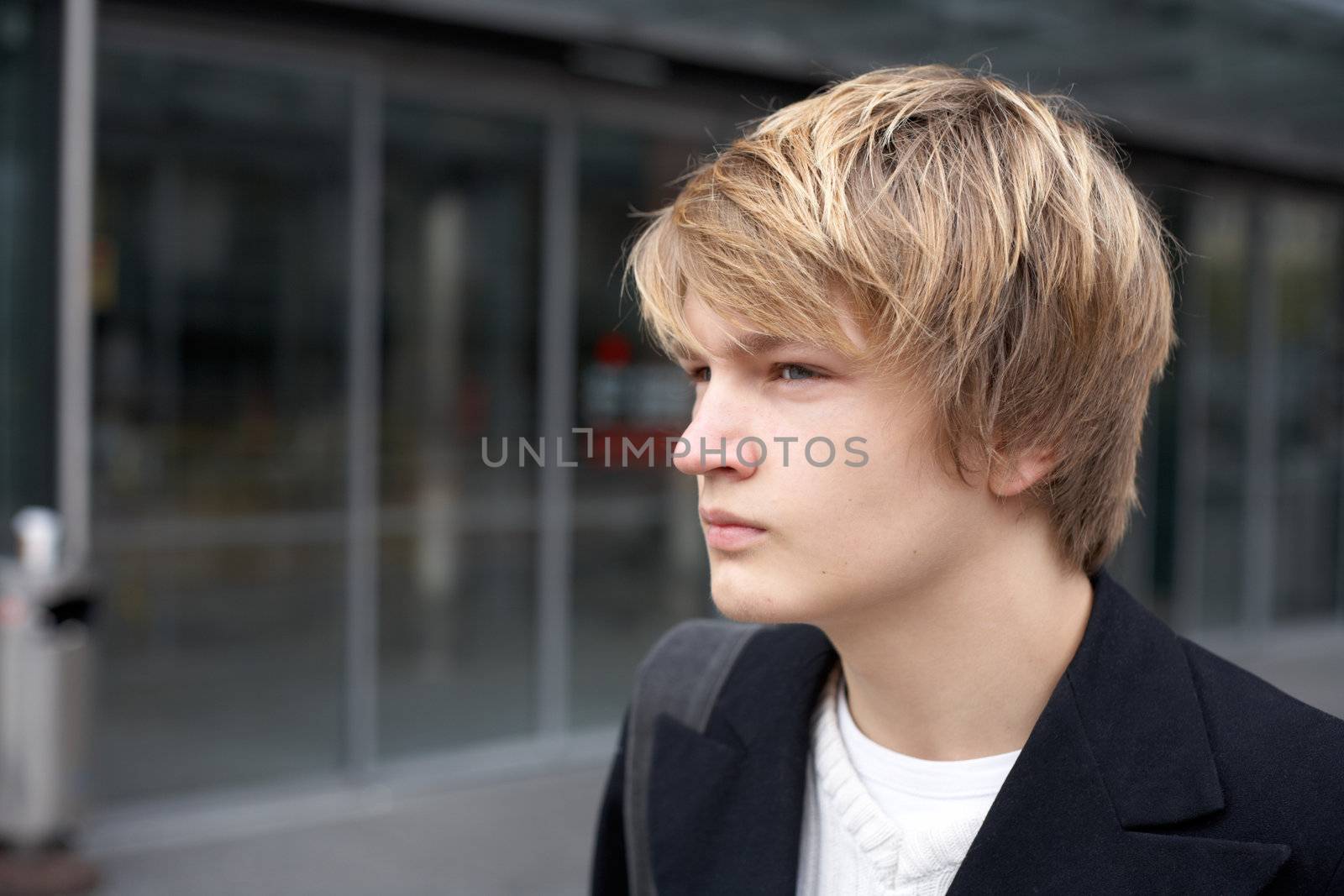 Thoughtful teenage boy outside modern building entrance
