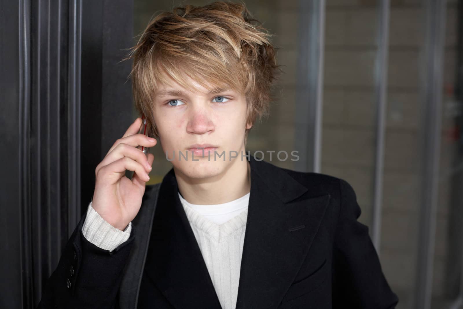 Teenage boy on mobile phone outside modern building