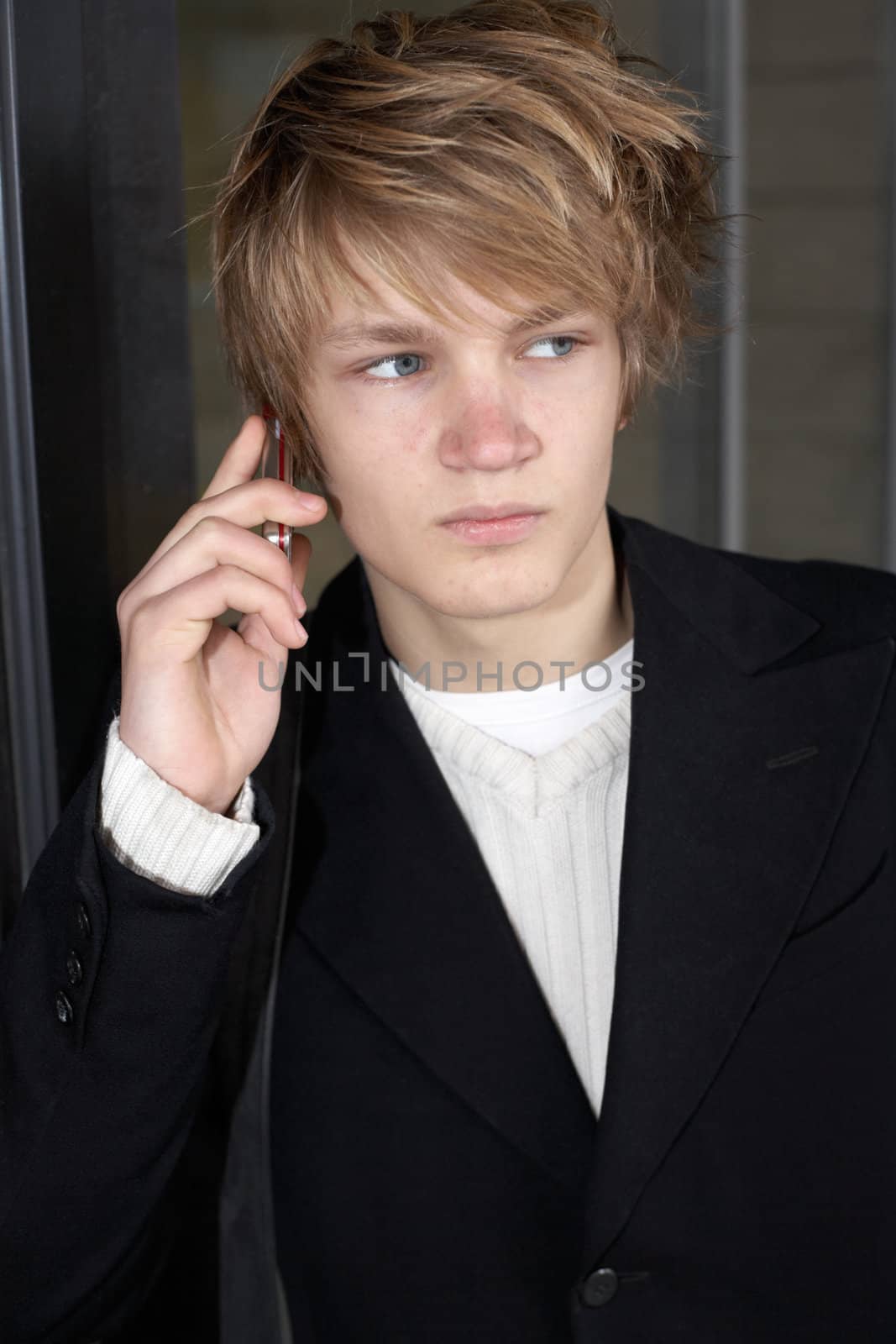 Teenage boy using mobile phone outside modern building