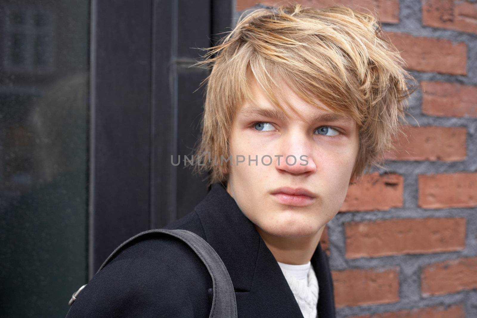 Teenage boy looking over shoulder by building wall