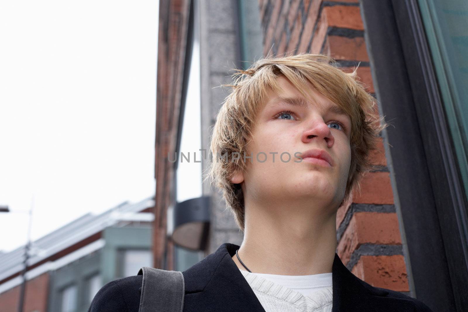 Teenage boy standing by building in street, low angle