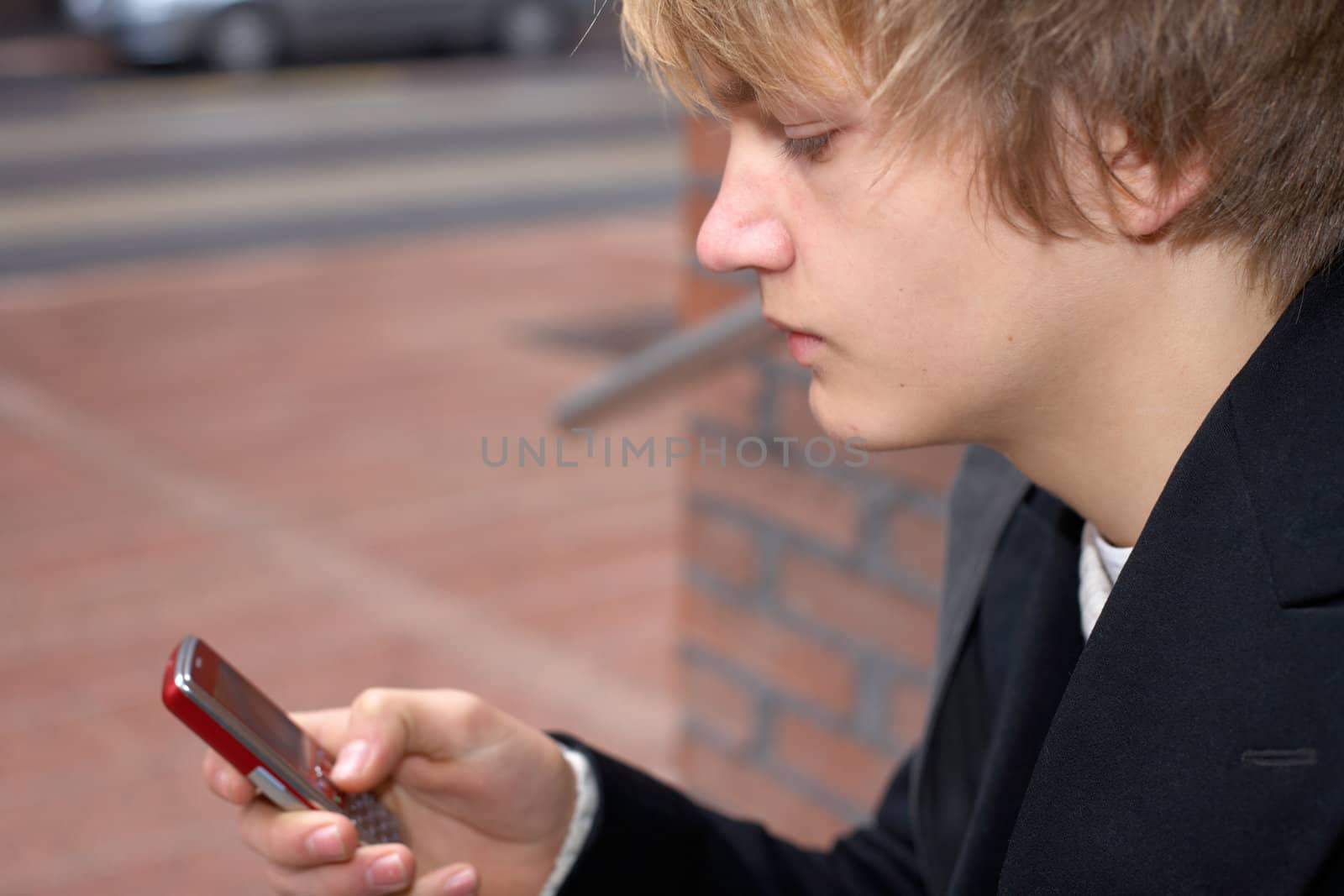 Teenage boy text messaging with mobile phone, close-up
