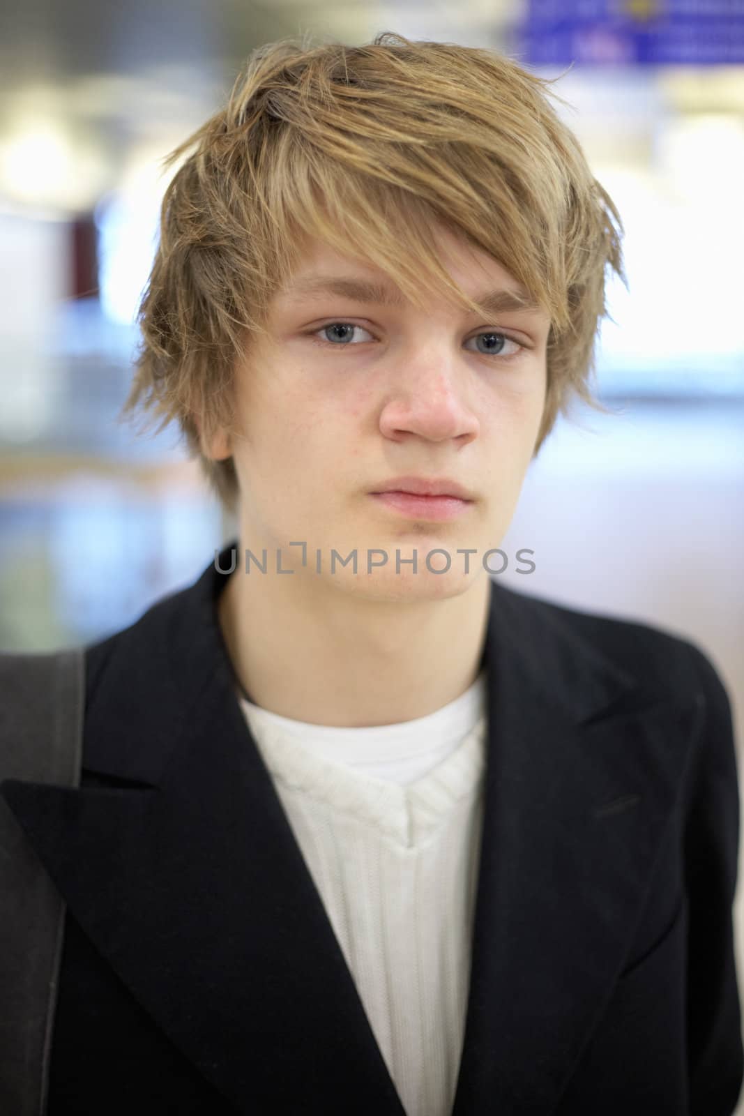 Teenage boy inside modern building, looking at camera