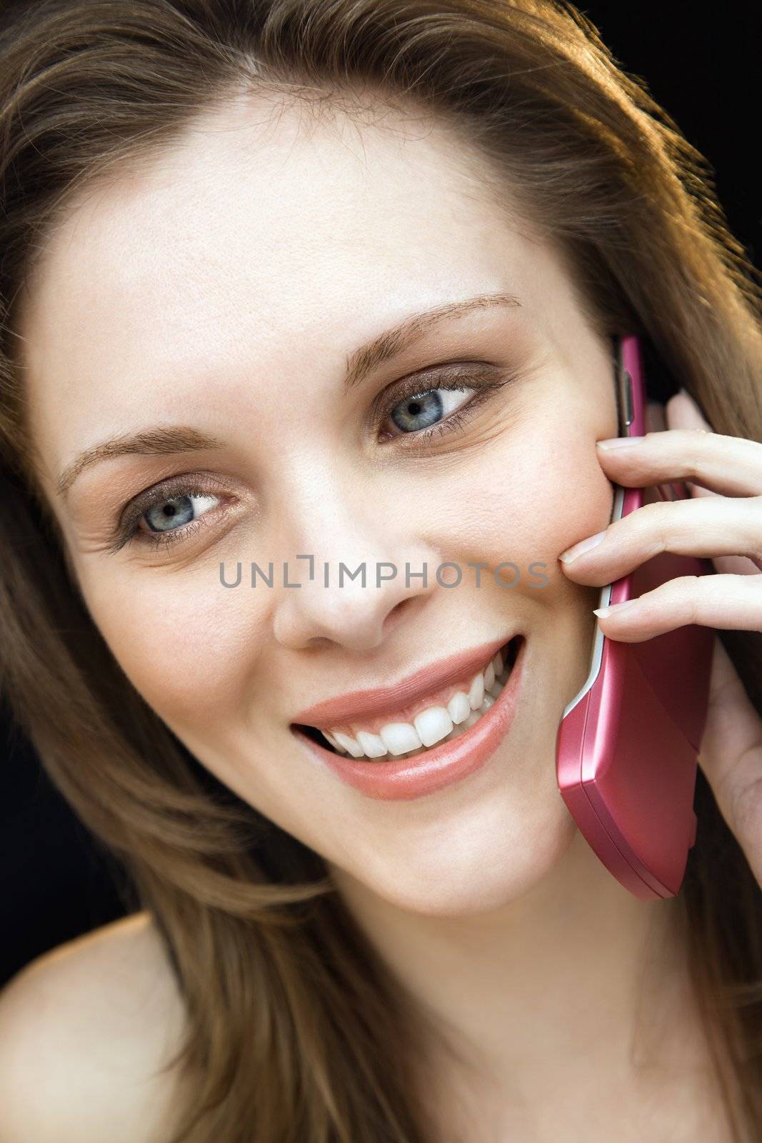 Close up portrait of young adult female talking on mobile phone and smiling.