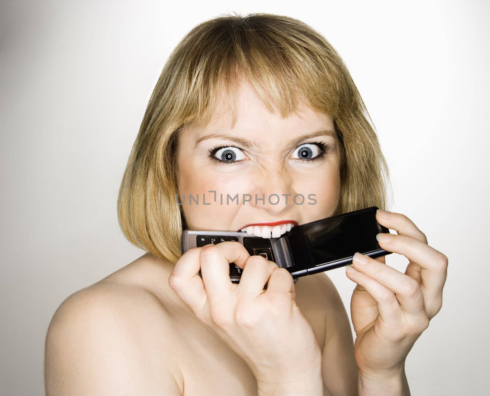 Woman biting phone. by iofoto