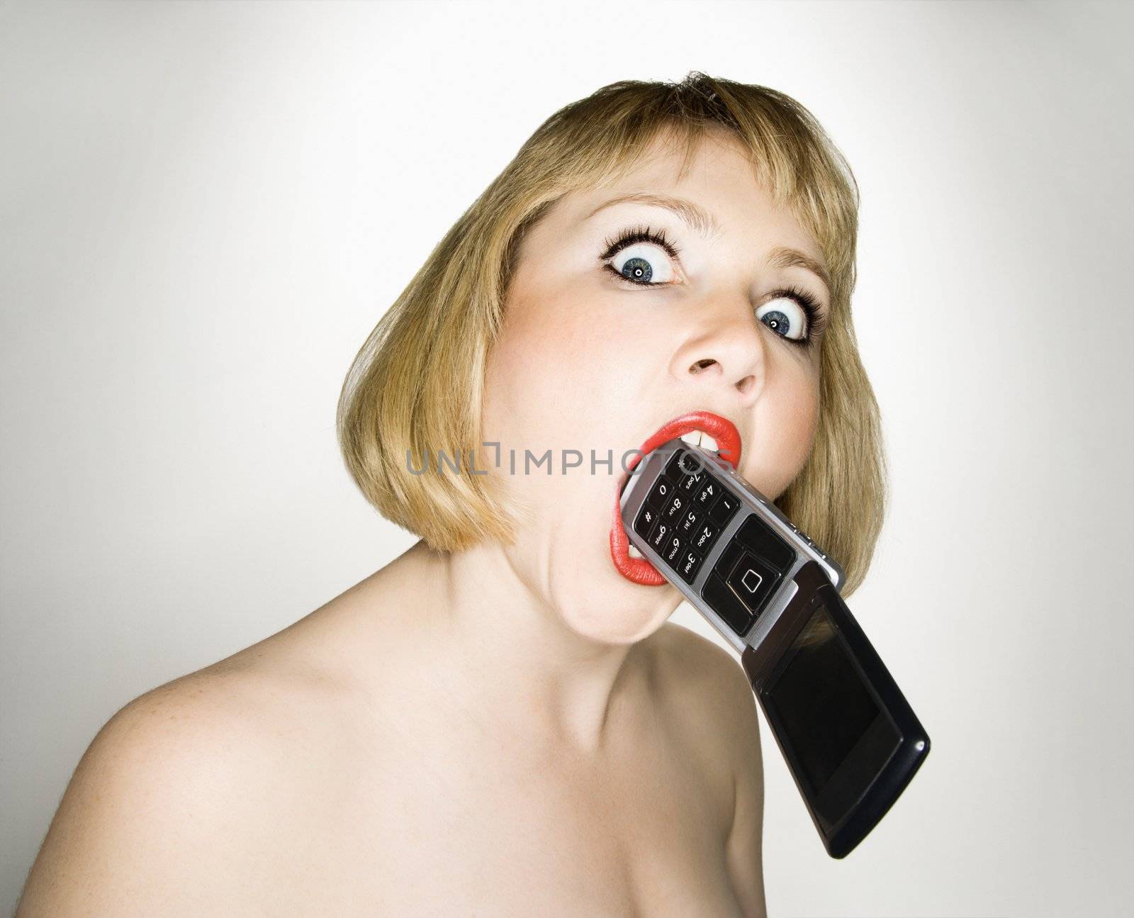Crazy woman biting phone. by iofoto