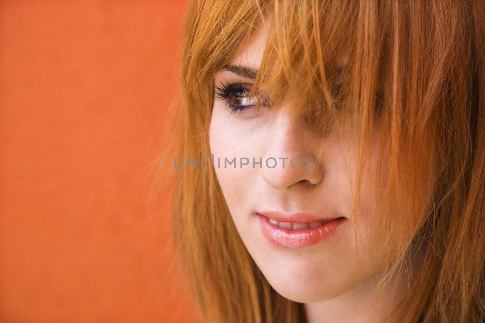 Close-up portrait of smiling young redheaded female looking mischievious.