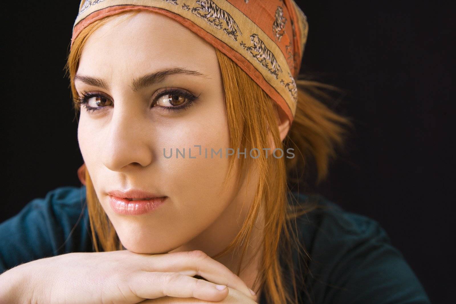 Young redheaded woman wearing cap looking at viewer with serious expression.