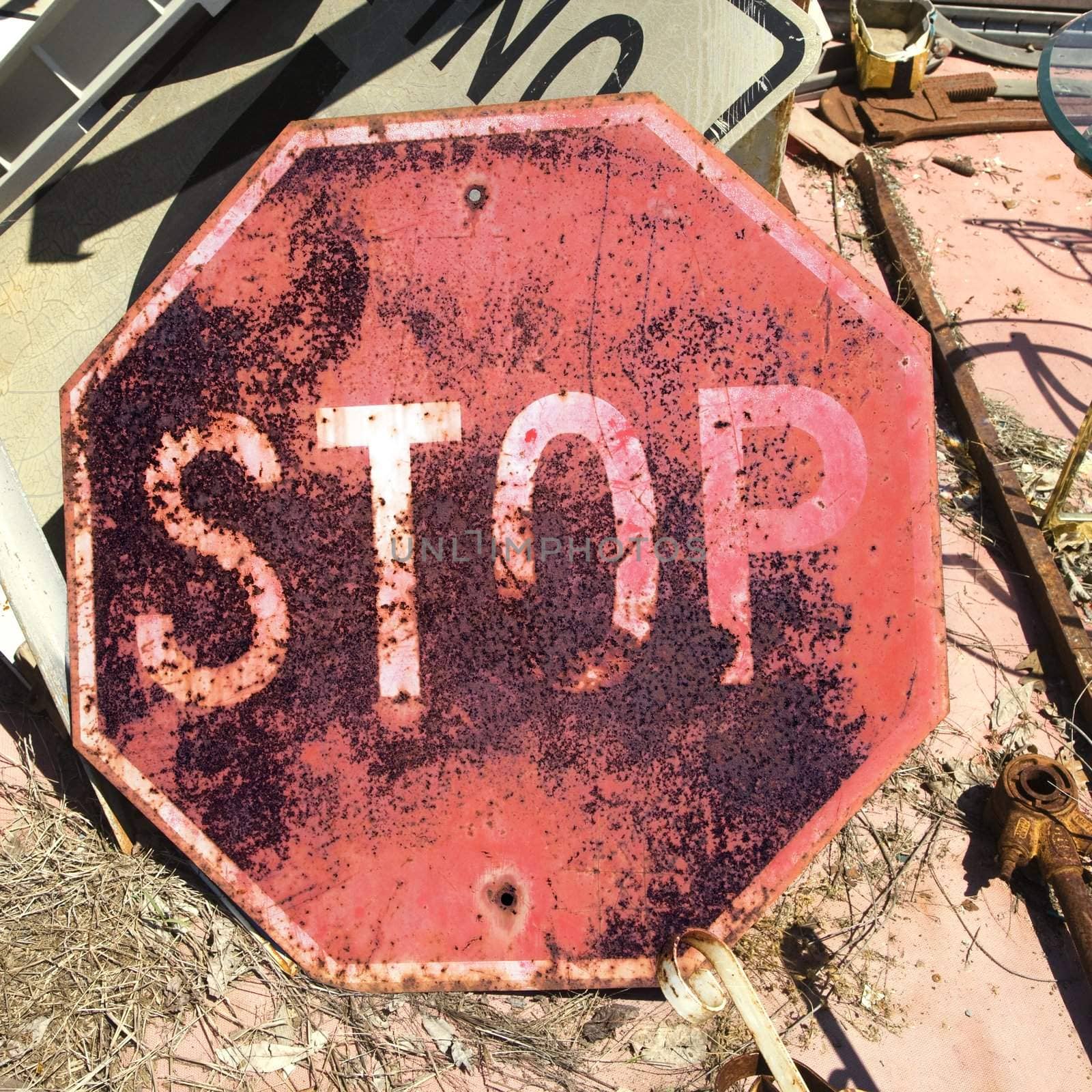 Rusty old stop sign on ground.