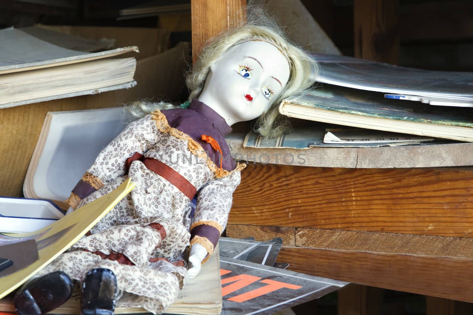 Old baby doll sitting on shelf.