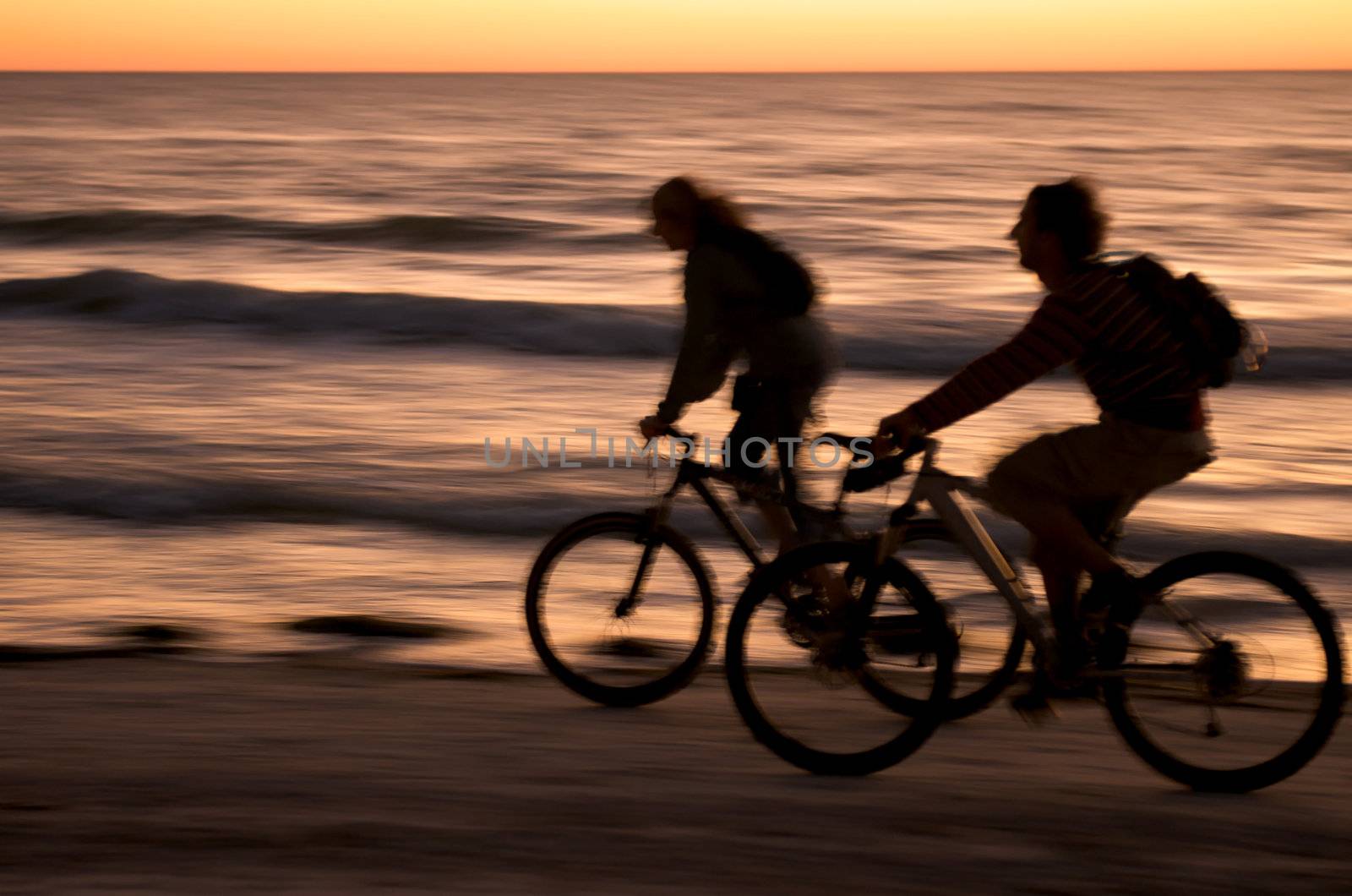 Couple ryding bycicle at sunset in Honeymoon Island, Florida.