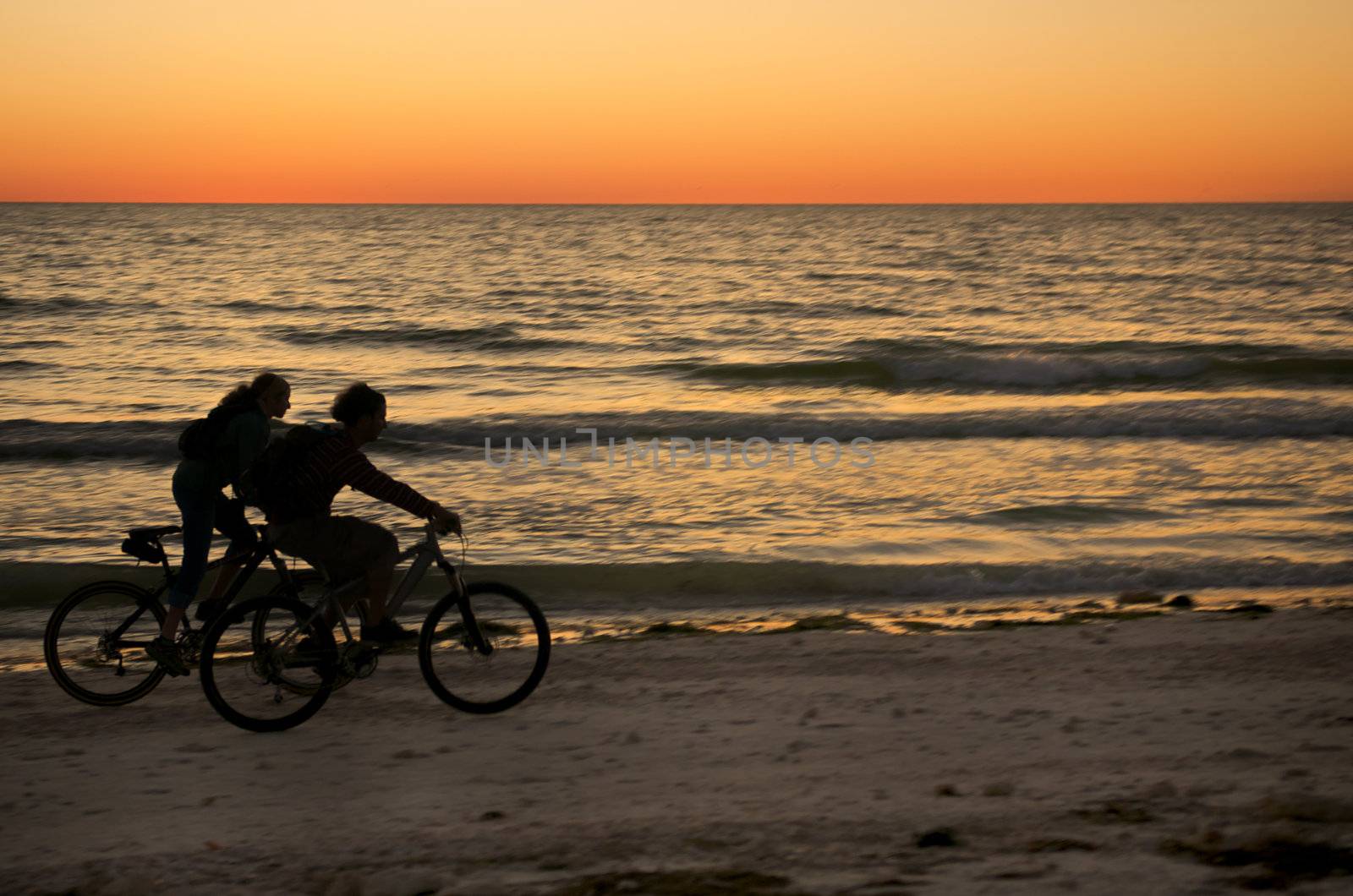 Couple ryding bycicle at sunset in Honeymoon Island, Florida.