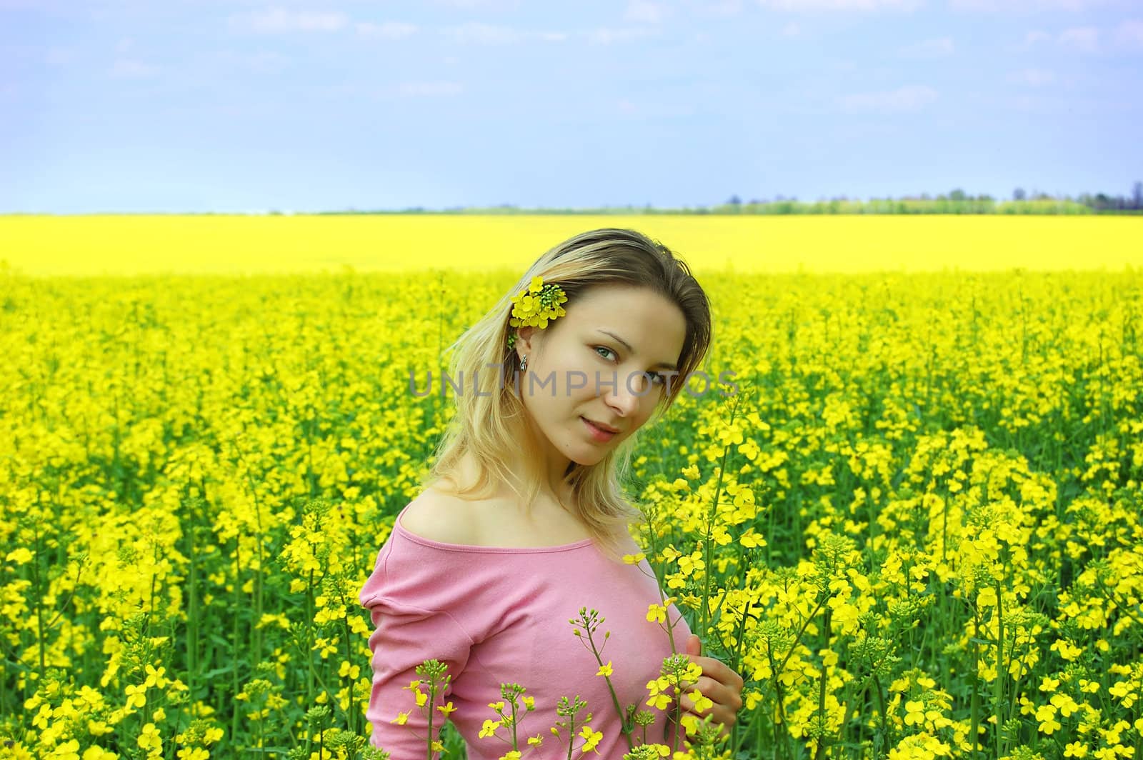 Beautiful girl among blooming rape oilseed field blooming
