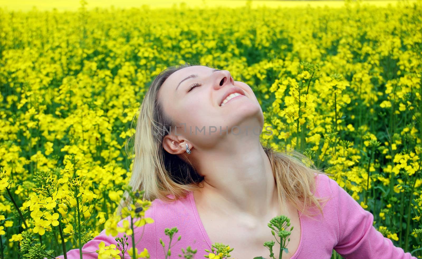 Beautiful girl among blooming rape oilseed field blooming
