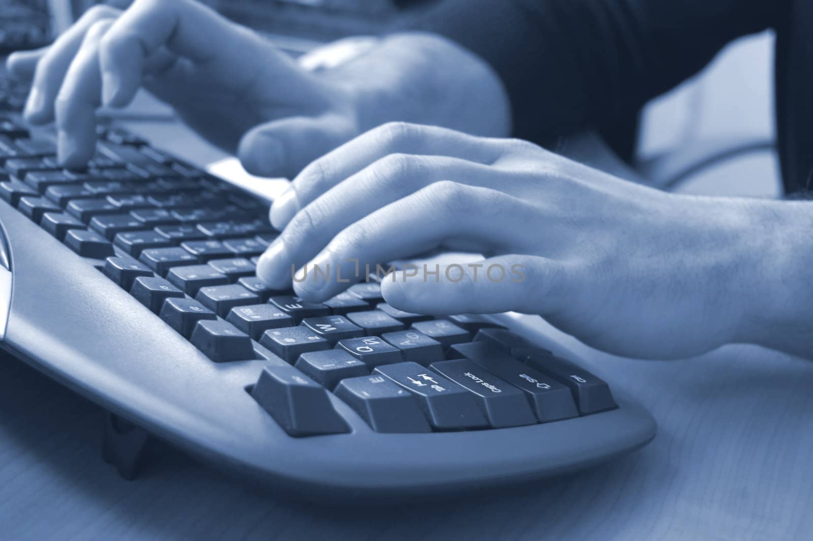 male hands typing on keyboard, blue toned