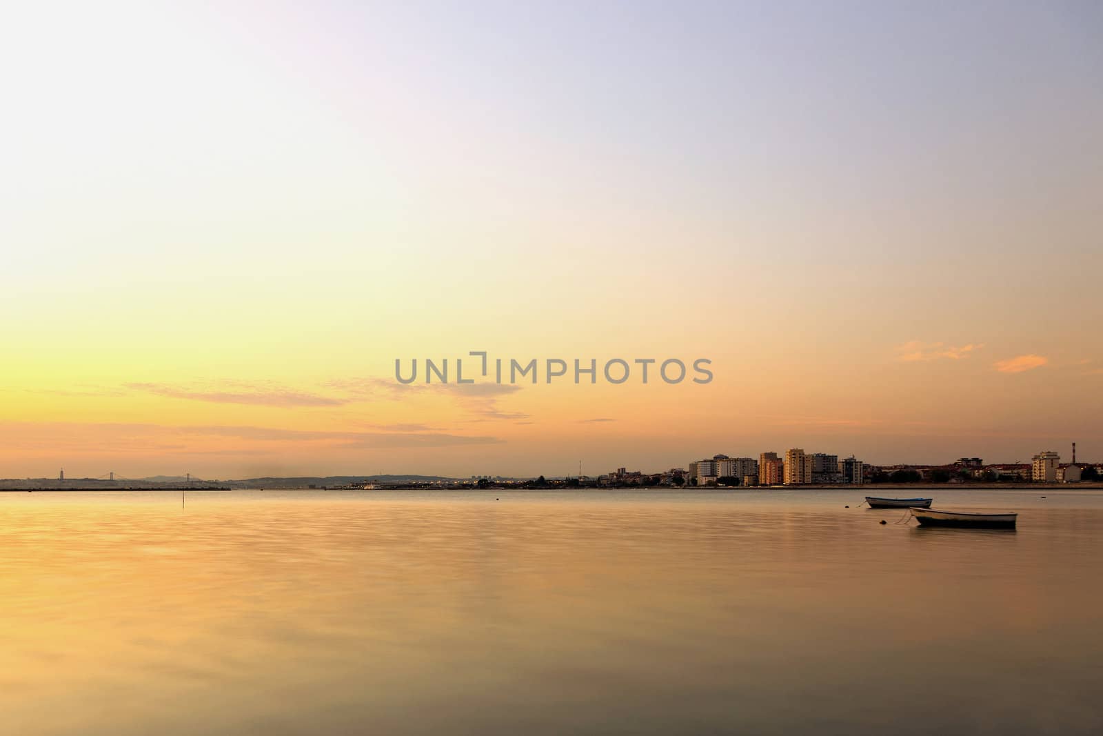 The city and the river with two small boats at sunset.