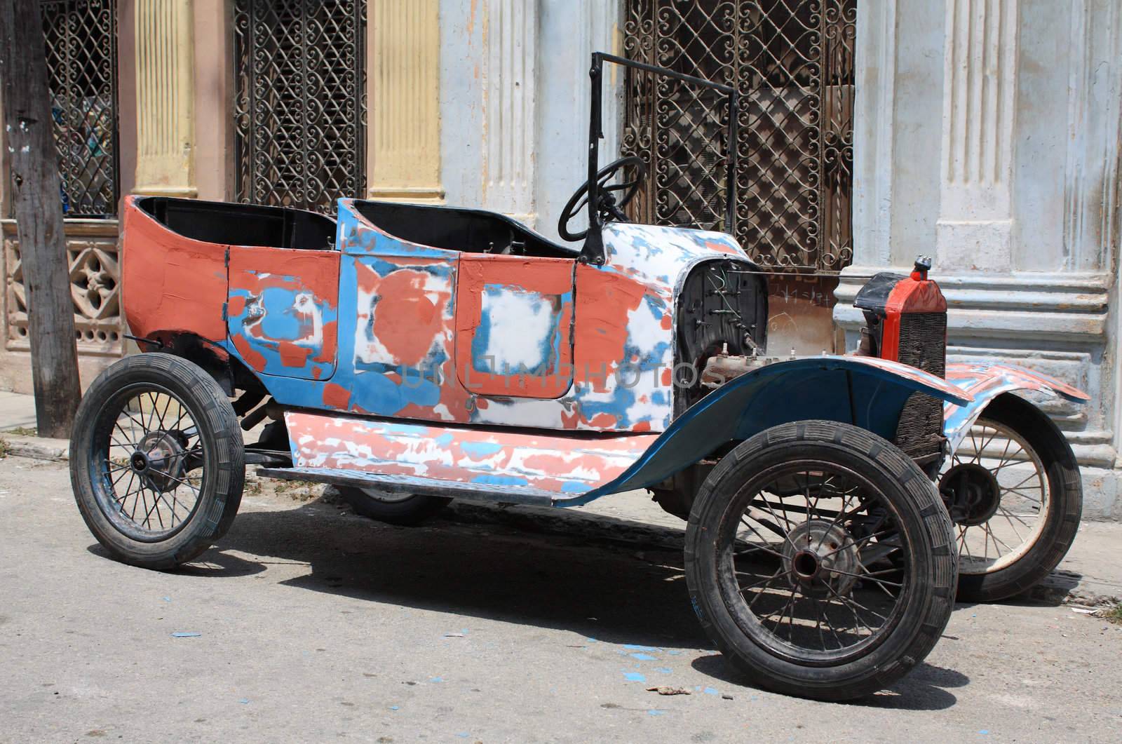 A colourful tattered open top vintage car in a street of Havana, Cuba.