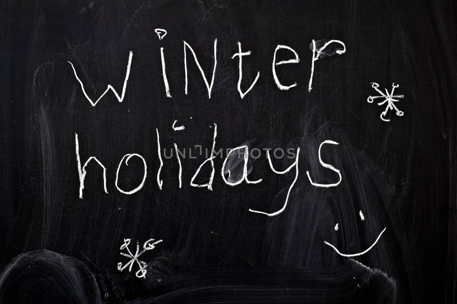 Inscription "winter holidays", written by a child's hand on the chalk board