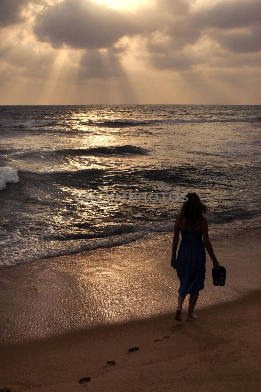 The lonely girl on a beach on sunset