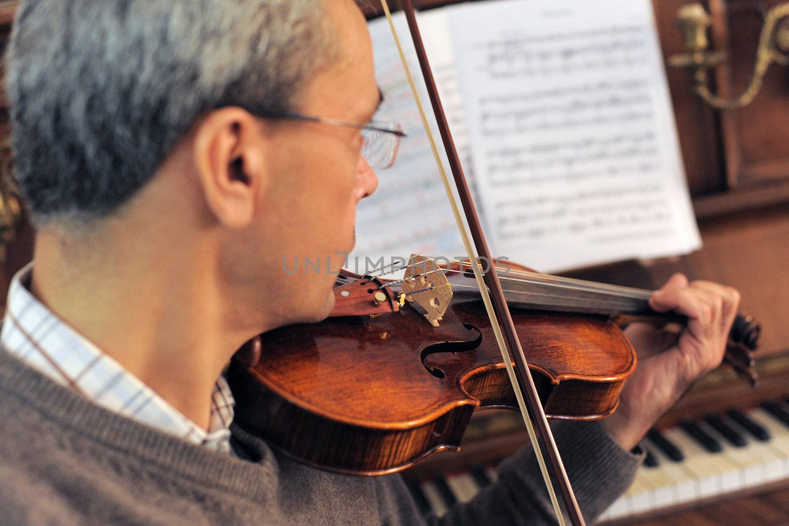 violinist with piano in the background, focus on the violin