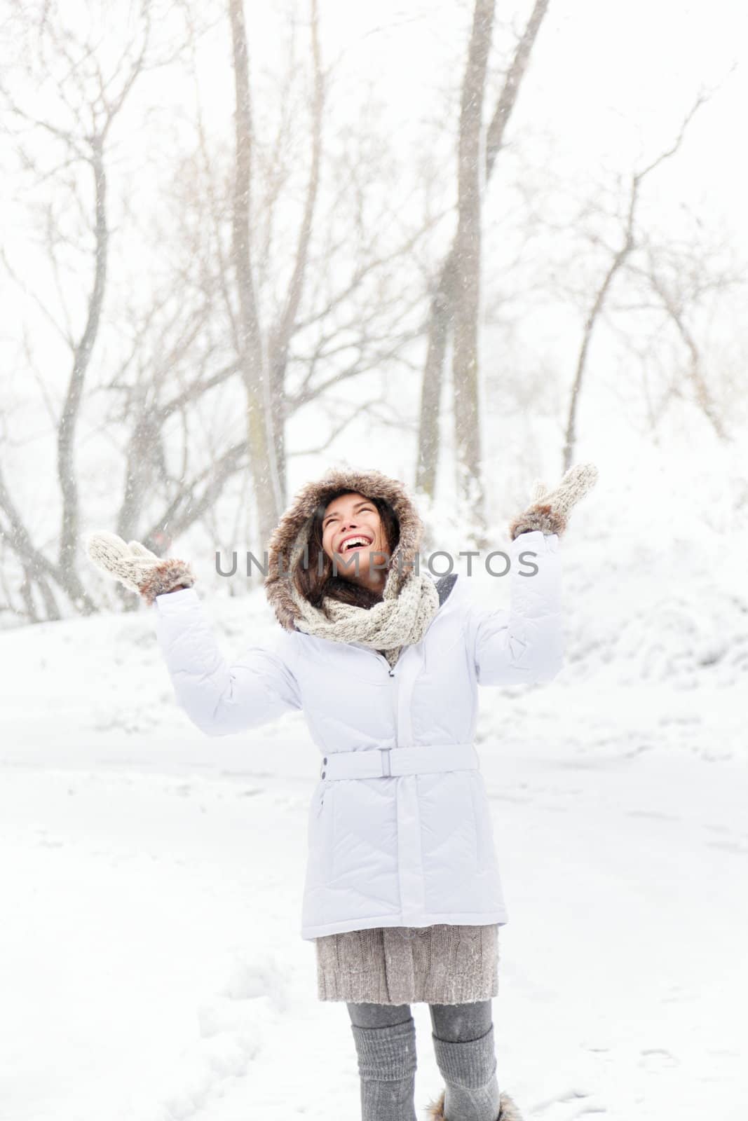 happy winter woman playing in snow on snowing winter day. Smiling happy and joyful multicultural Asian Caucasian young woman outdoors.