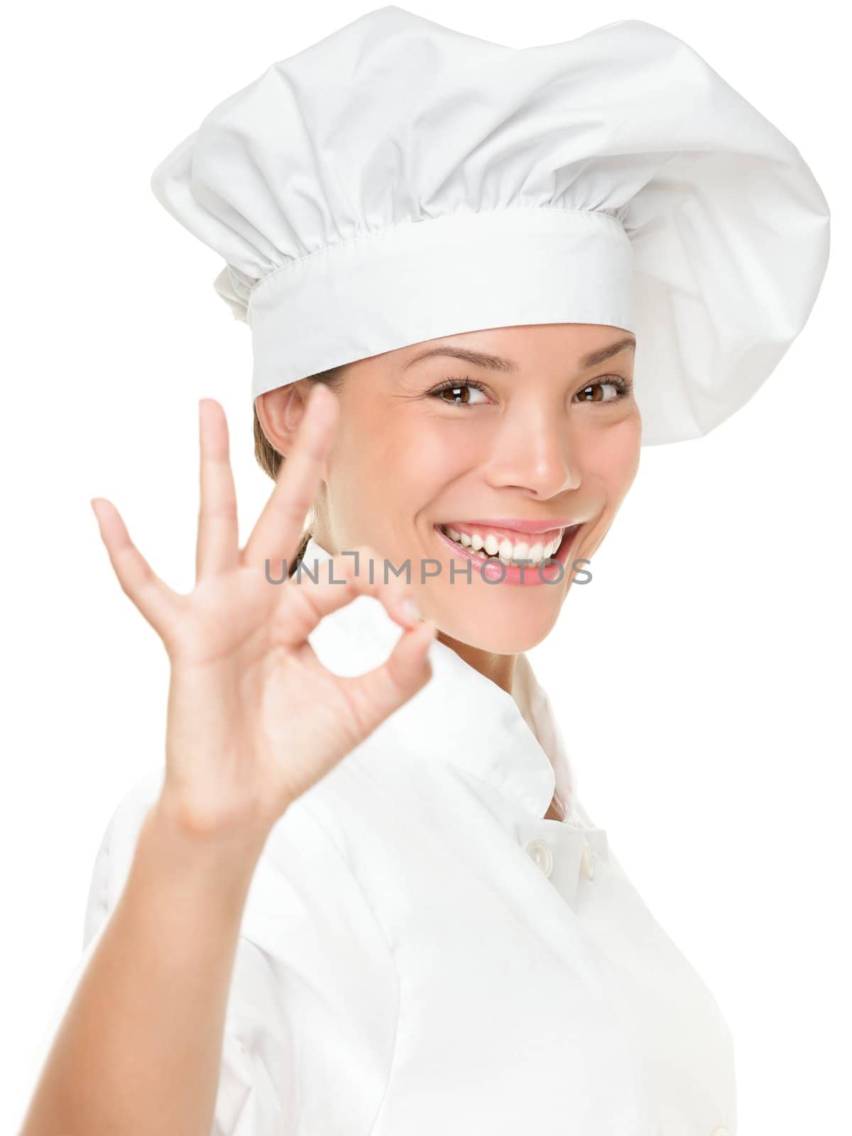 Chef baker or cook showing ok hand sign for perfection. Woman chef smiling happy and proud. Portrait of female cook wearing chefs hat isolated on white background. Mixed race Asian Caucasian female model.