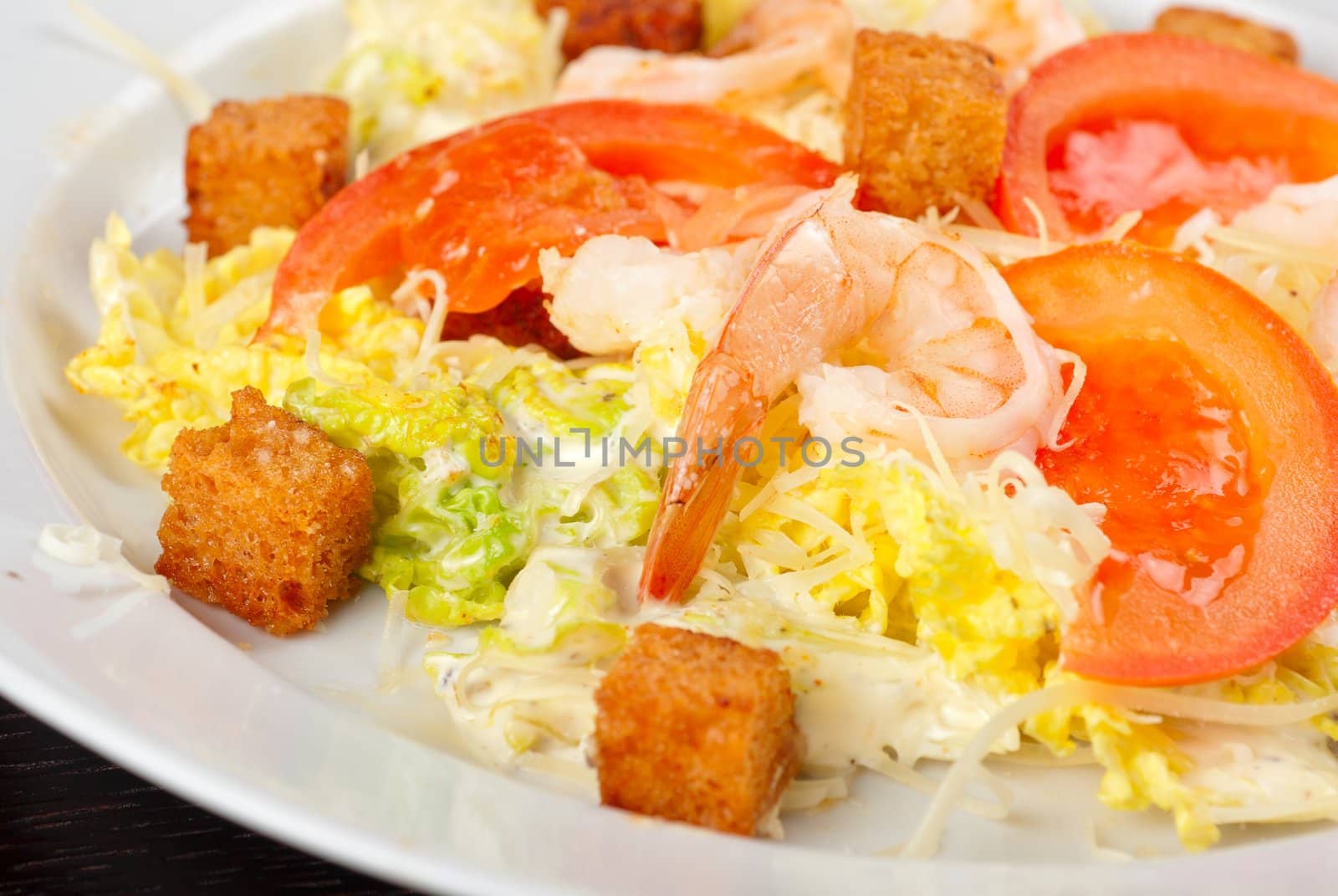 Salad of tiger shrimps, lettuce, chinese cabbage, tomato, garlic rusk, parmesan cheese and sauce