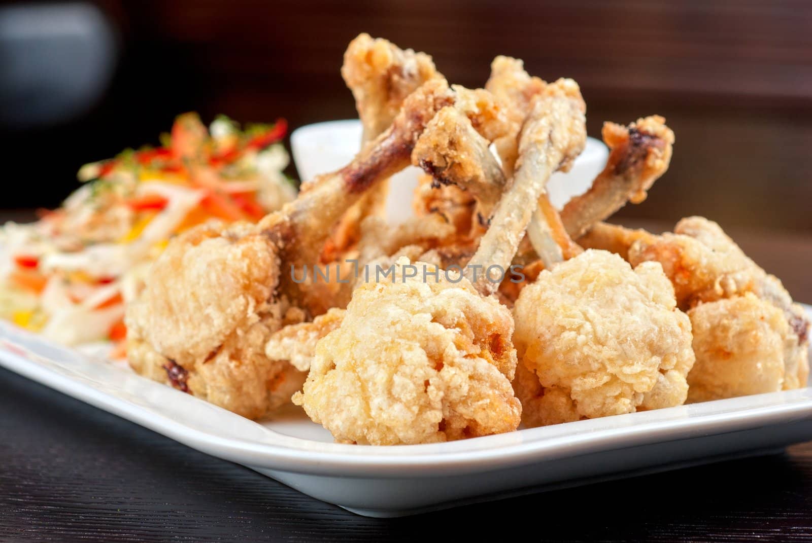 Fried chicken wings garnished with fresh vegetables with Teriyaki sauce
