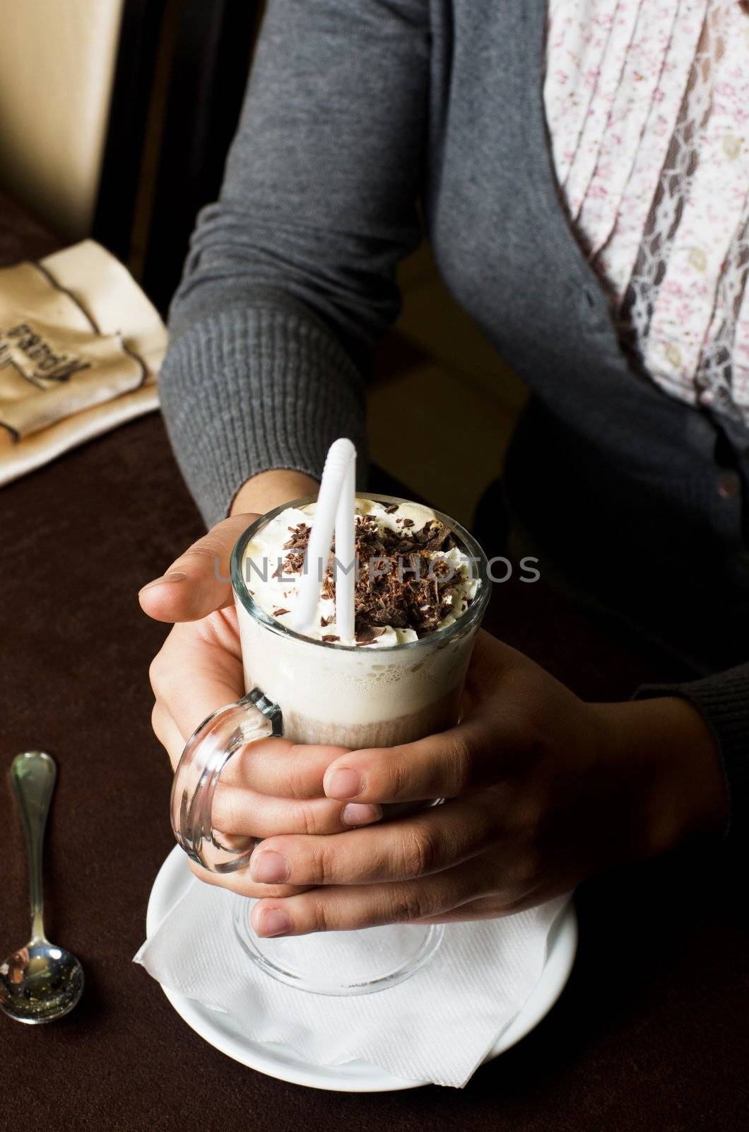 Closeup of female hands holding cup of latte