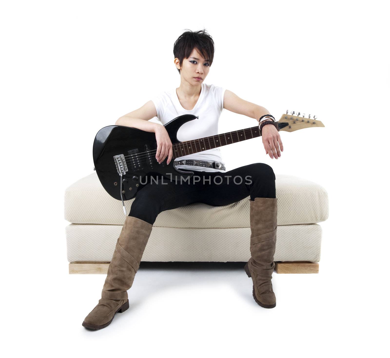 Punk Rockstar holding guitar sitting on sofa isolated in white