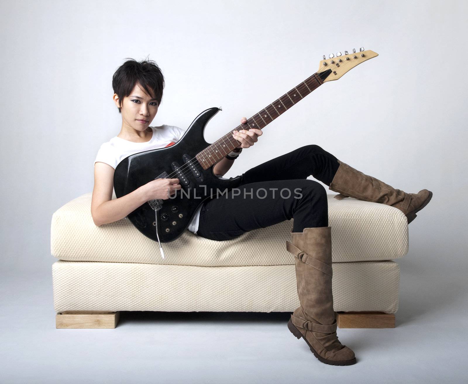 Punk Rockstar holding a guitar sitting on sofa.