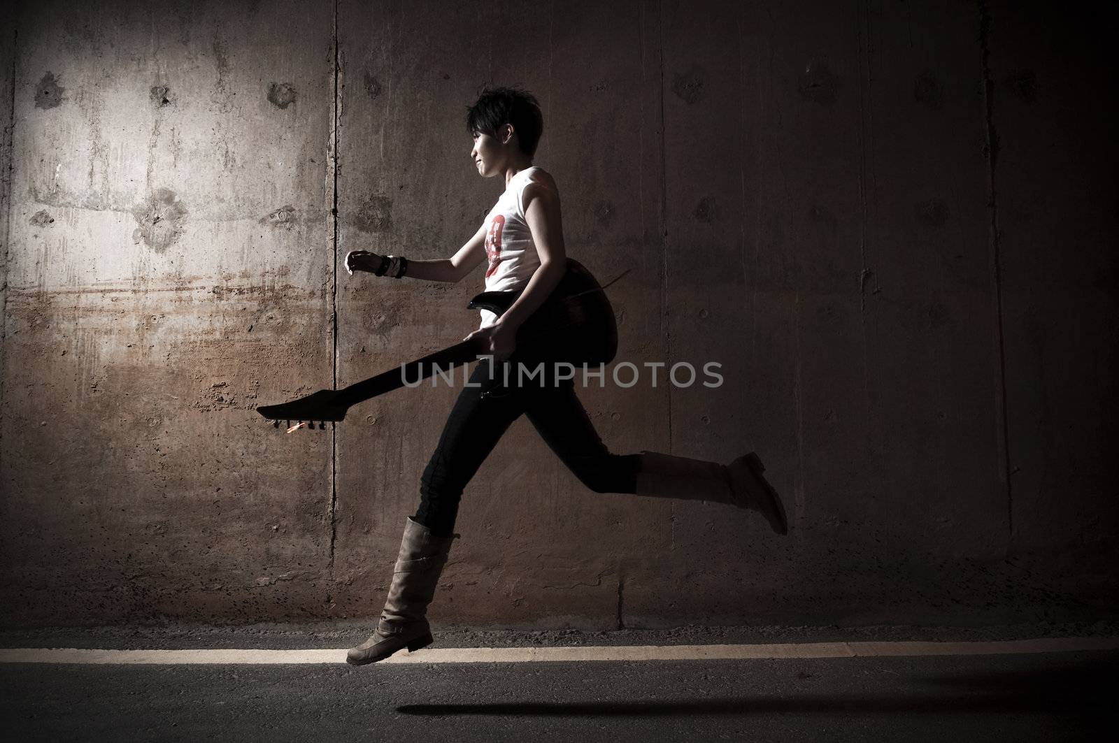 Rockstar running with her guitar outdoors in night.