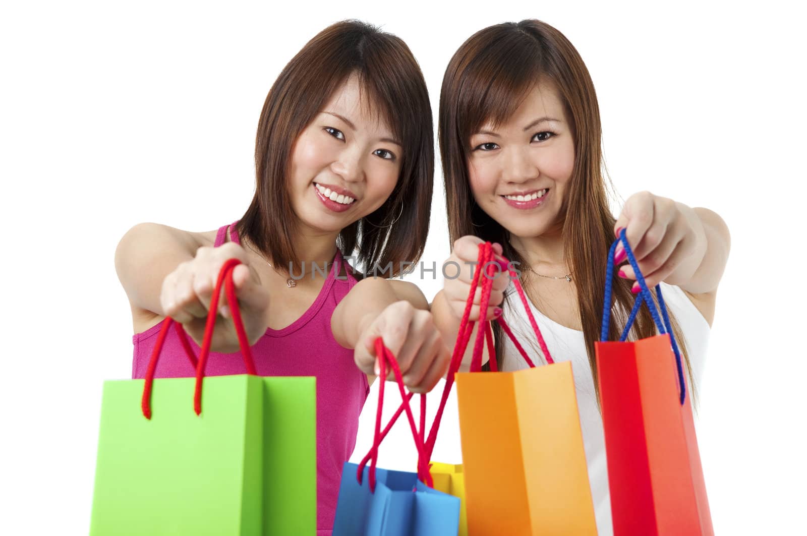 Happy Asian girls showing their shopping bags against white background.