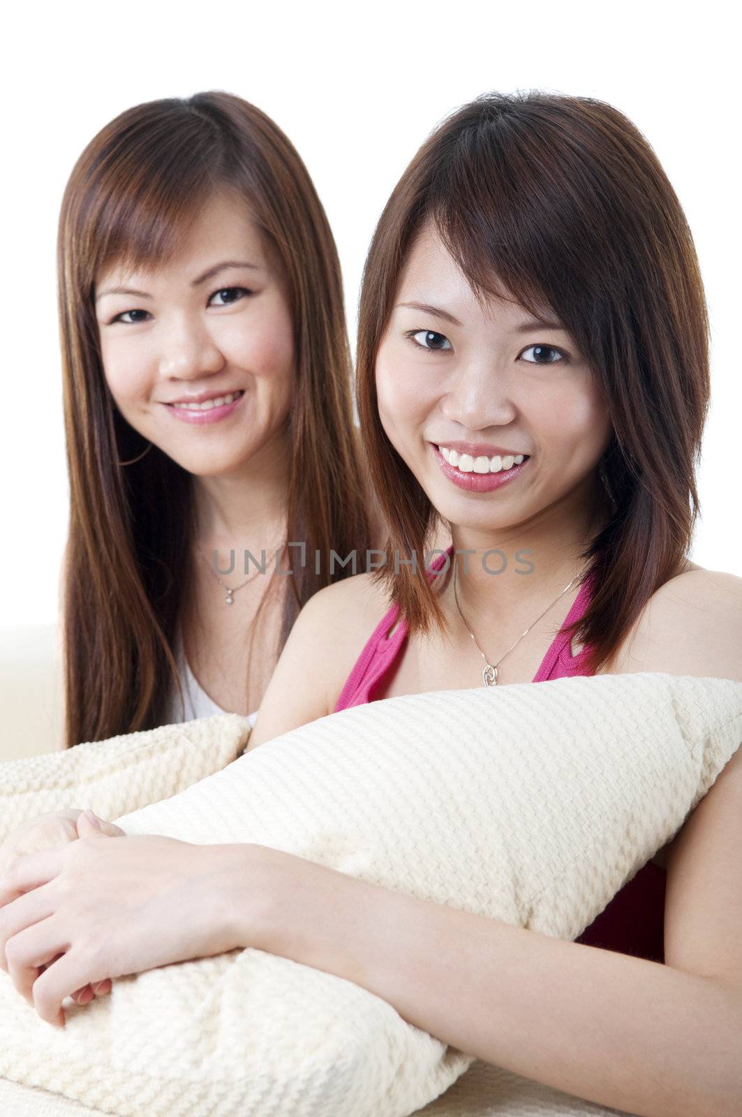 Two girls sitting on sofa, looking at camera.