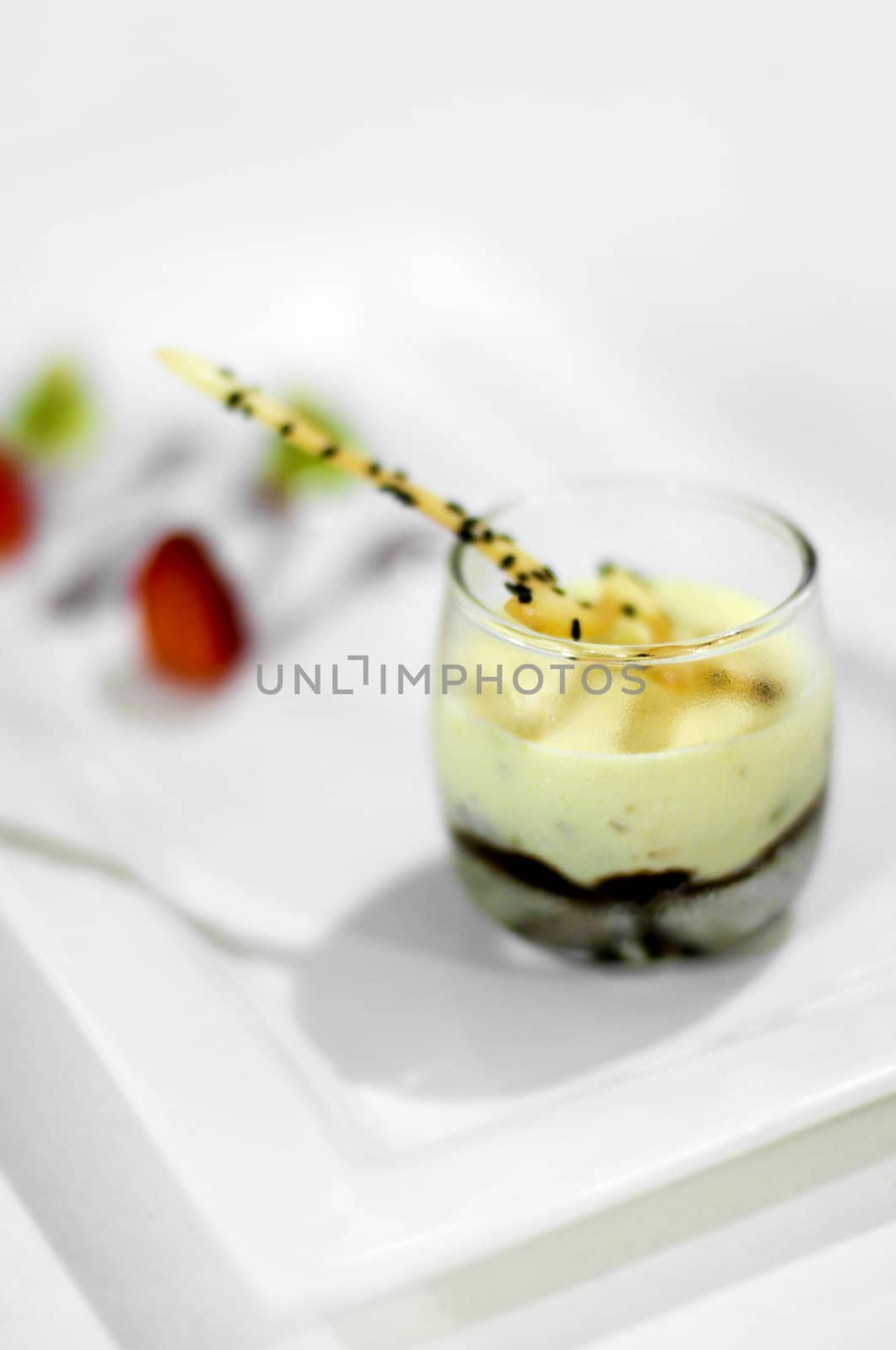 A creamy dessert with crushed pistachio nuts and chocolate ganache, served with fresh caramel fruits