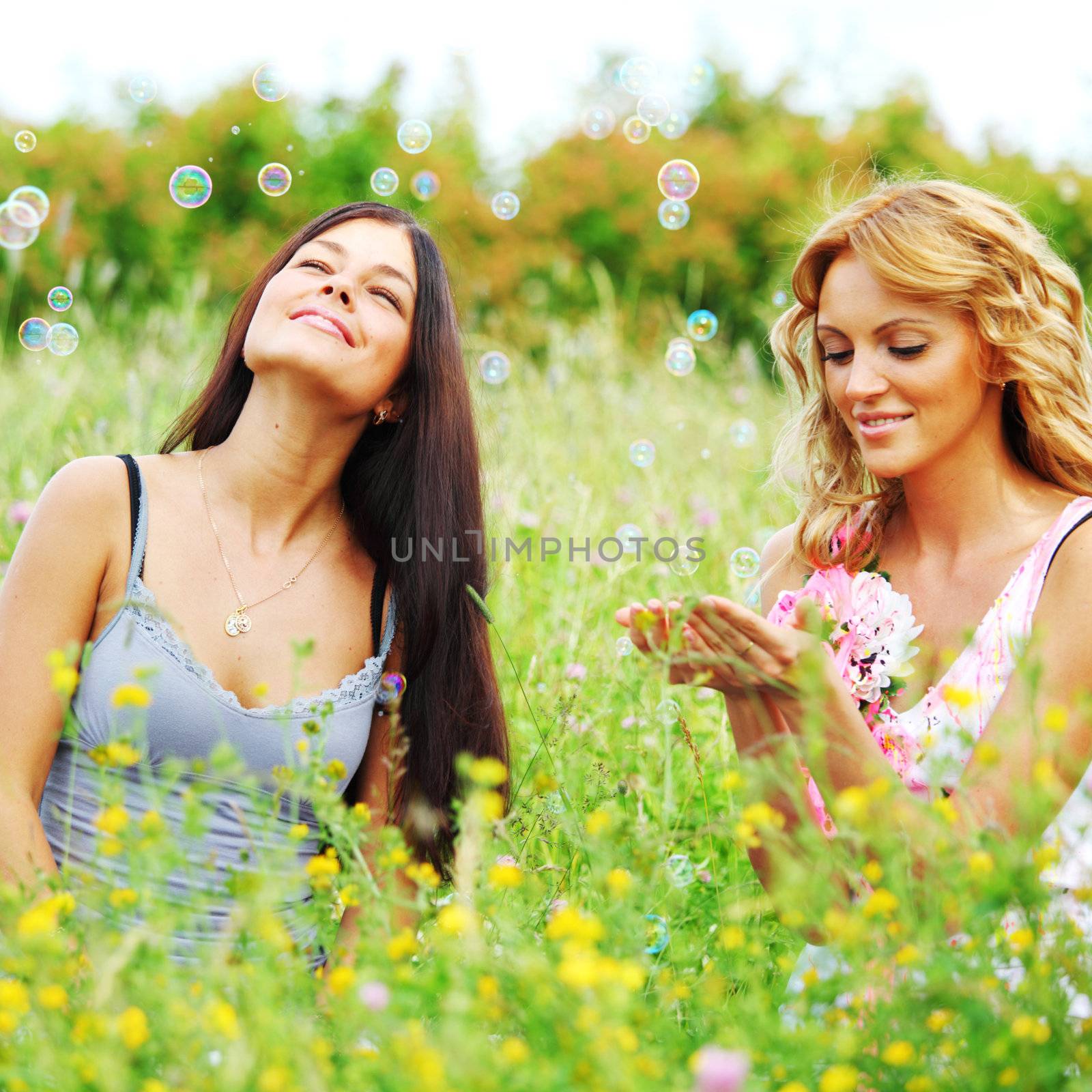 girlfriends on green grass field in soap bubbles