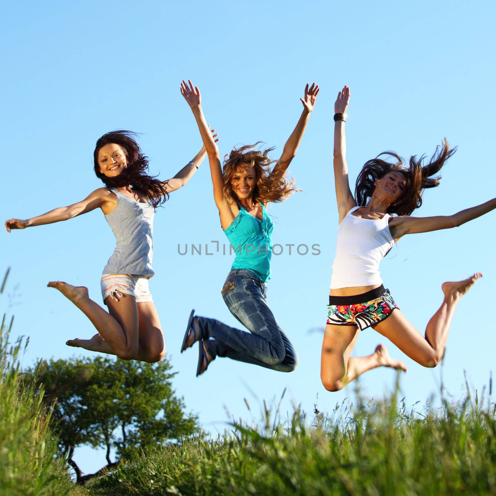 girlfriends jump in green grass field