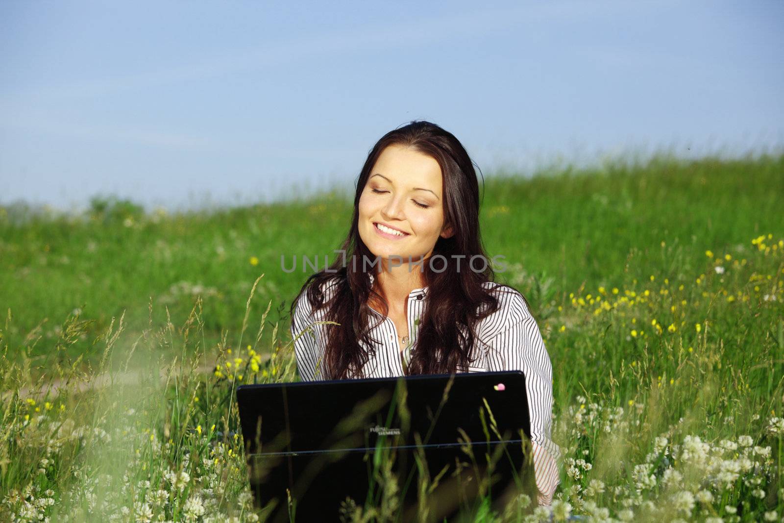 girl with laptop on green grass