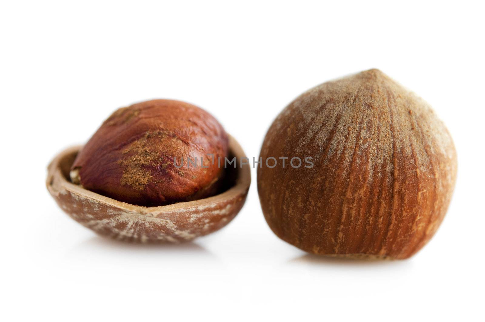 Closeup of whole and cracked hazelnuts. Isolated on white background.