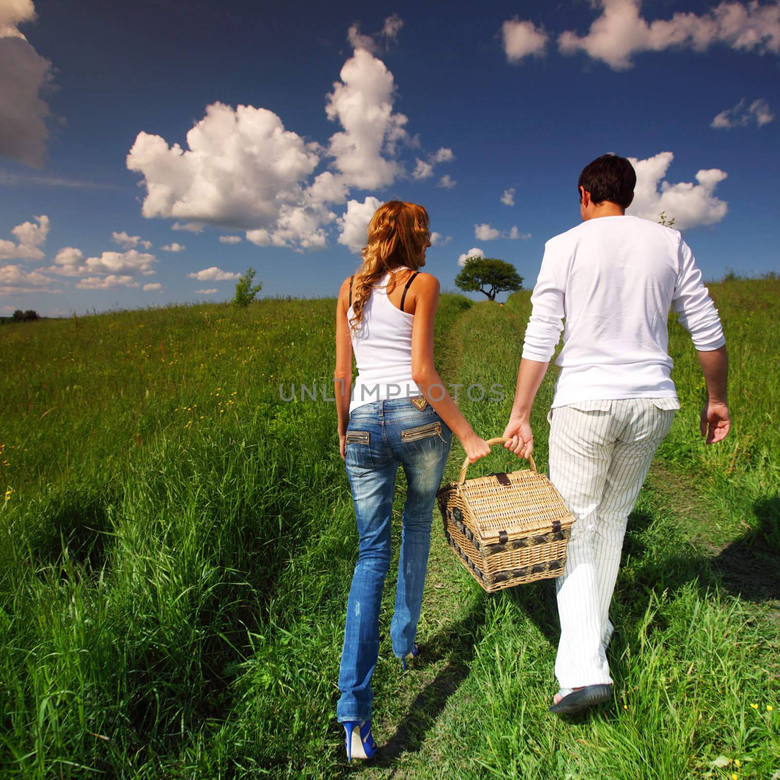 man and woman walk on picnic in green grass