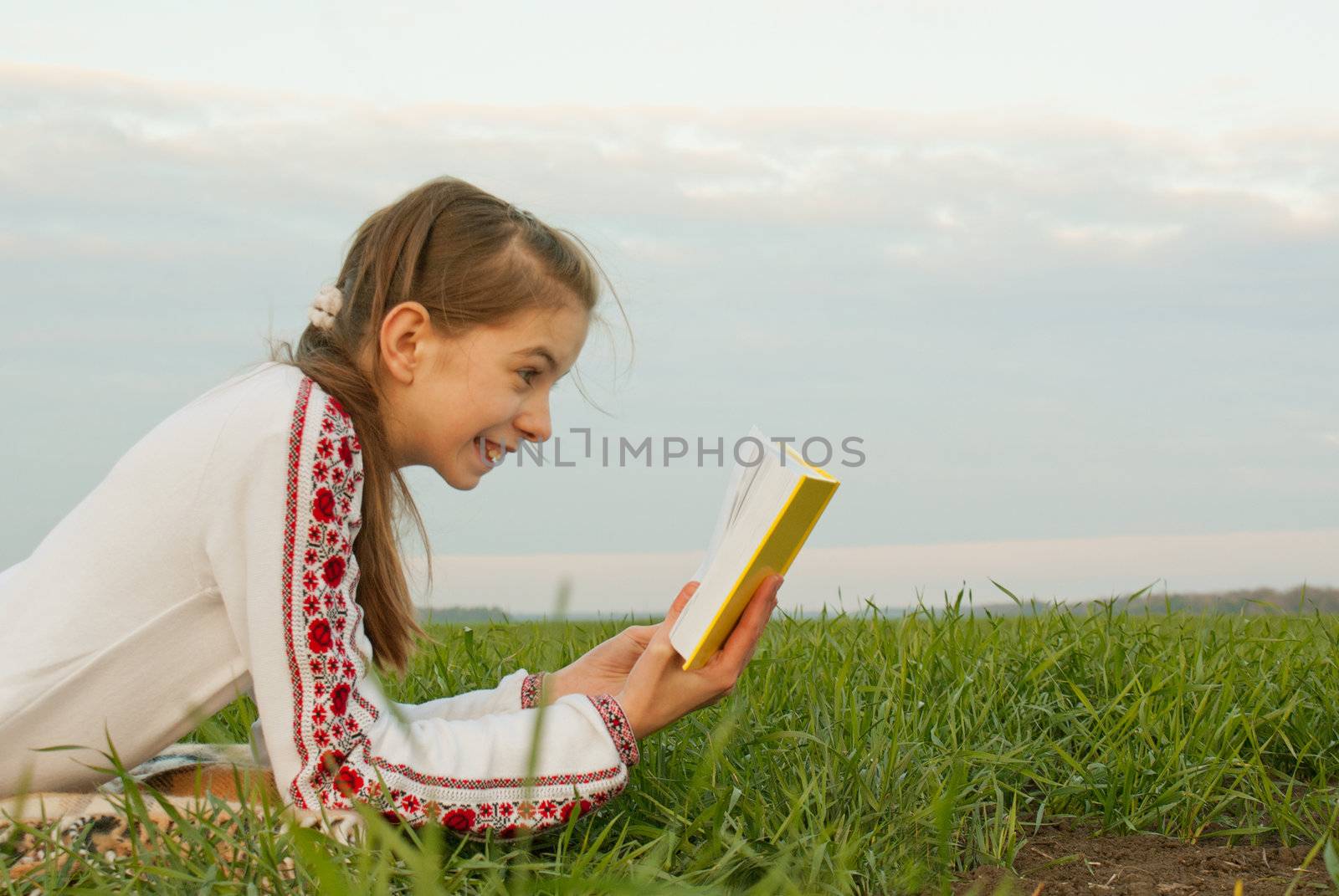 Teen girl reading a book at a field by AndreyKr