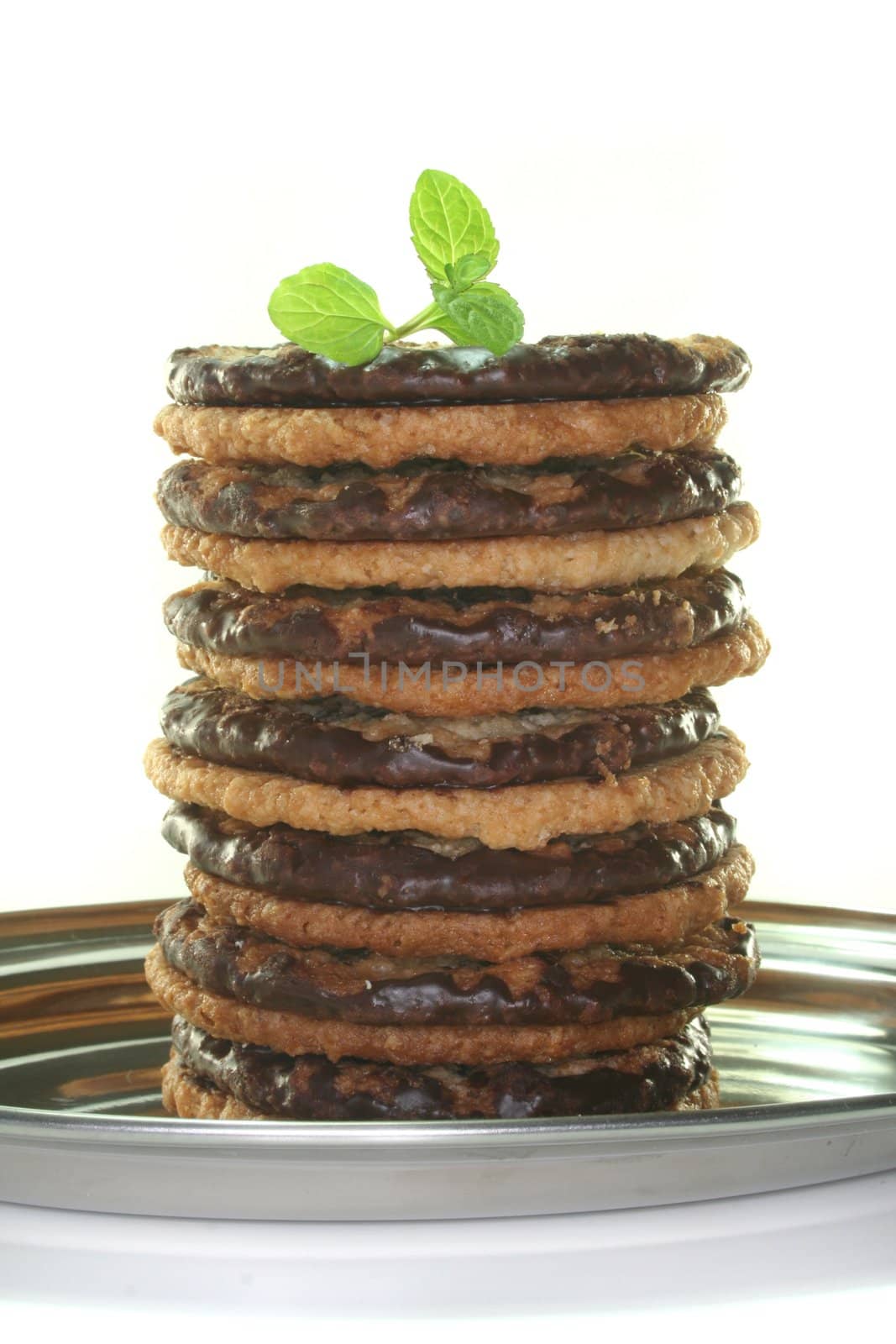Oat cookies with chocolate filling on a tray with mint on a white background
